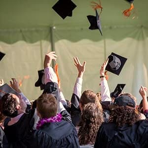 Absolventinnen und Absolventen werfen ihre Hüte in die Luft