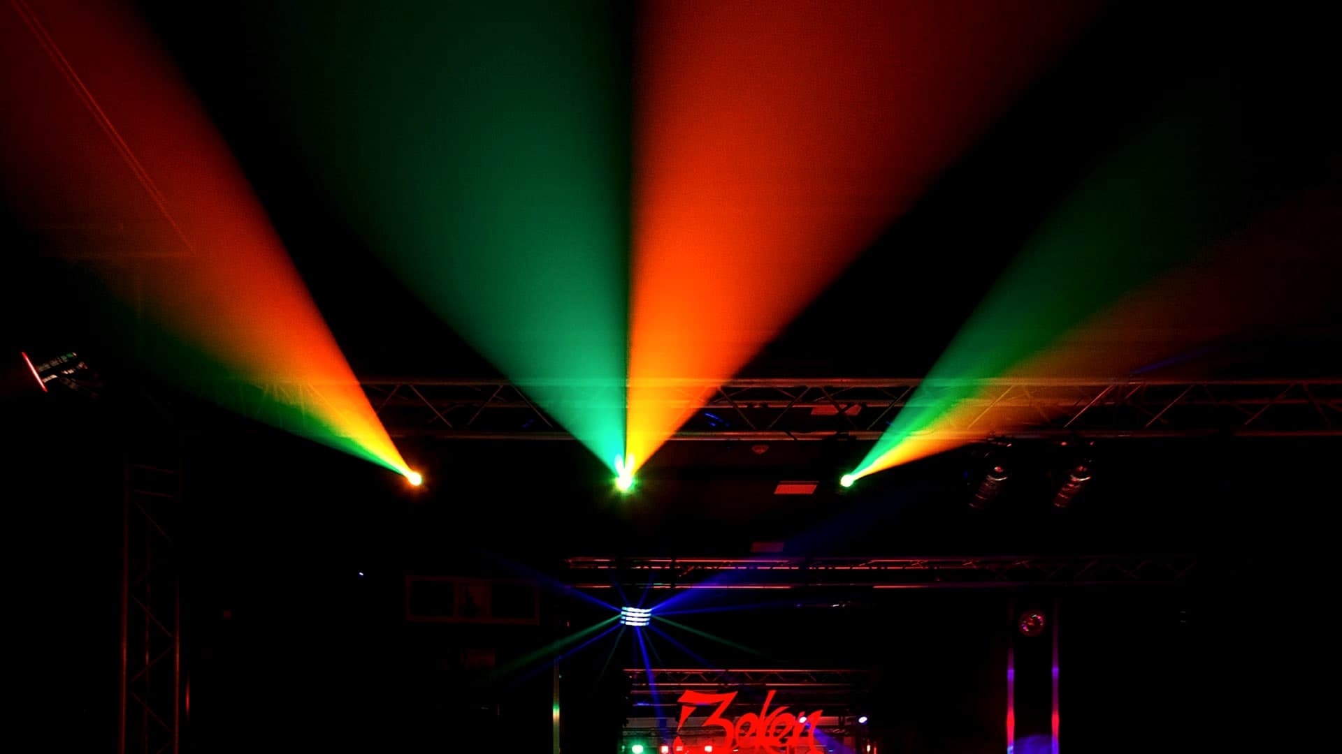 Bunte Lichtkegel in Rot, Grün und Orange über der Bühne