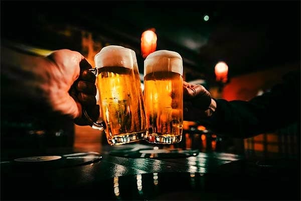 Zwei Gäste stoßen an der Bar mit frisch gezapftem Bier an
